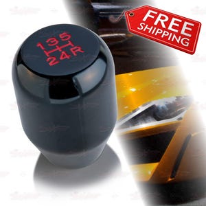 May include: A black shift knob with red gear markings, including 1, 3, 5, R, 2, and 4. The shift knob is glossy and has a rounded top. The image also includes a red tag with the words "FREE SHIPPING".