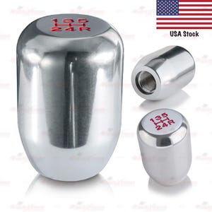 May include: A polished chrome shift knob with red gear markings. The top of the knob displays the gear pattern: 1, 3, 5, 2, 4, and R. The image includes multiple views of the shift knob.