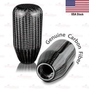 May include: Two carbon fiber car shift knobs. One is upright, the other is angled. The knobs are black with a woven pattern. The text "Genuine Carbon Fiber" is printed on the image. The American flag and "USA Stock" are also visible.
