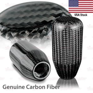 May include: Three carbon fiber car shift knobs. The knobs are black with a woven pattern. The text "Genuine Carbon Fiber" is at the bottom of the image. The American flag and "USA Stock" are in the upper right corner.