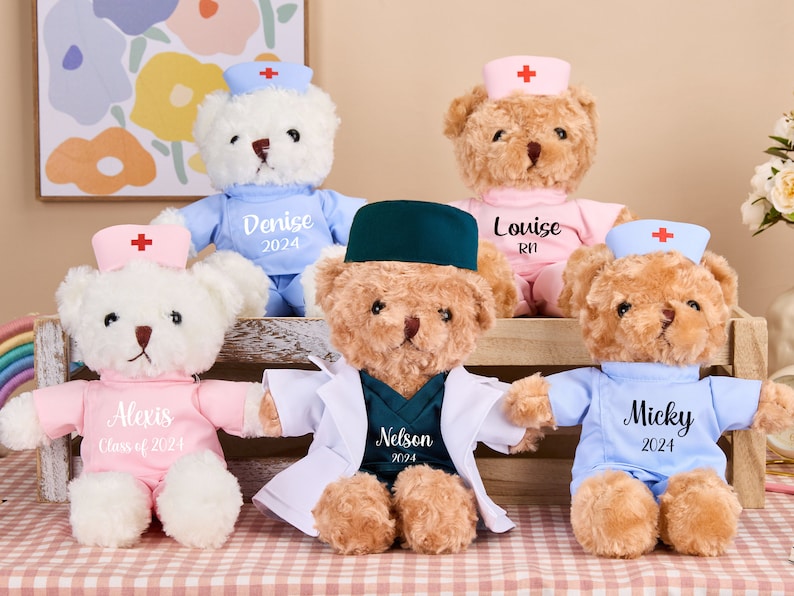 May include: Five plush teddy bears dressed in different medical uniforms. The bears are wearing hats with red crosses and have embroidered names and text on their uniforms. The names are Alexis, Denise, Louise, Micky, and Nelson. The text on the uniforms includes "Class of 2024", "RN", and "2024".