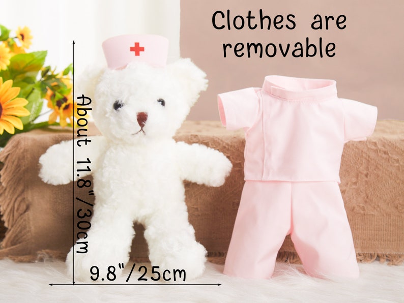 May include: A white teddy bear wearing a pink nurse's uniform with a red cross on the hat. The teddy bear is 11.8 inches tall and 9.8 inches wide. The clothes are removable.