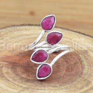 Puede incluir: Un anillo de plata con cuatro piedras de rubí rosa engastadas en un diseño de hoja.