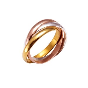 May include: An interlocking ring featuring three bands in gold, rose gold, and silver. The bands are intertwined, creating a distinctive design. The ring's metallic colours are set against a white backdrop. This piece of jewellery is a classic accessory.