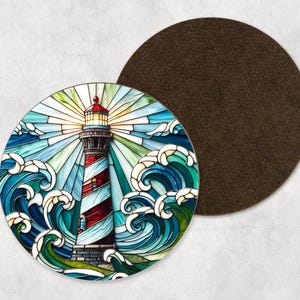 May include: A circular coaster with a lighthouse design, featuring red and white stripes, set against blue waves and a bright sky. A separate brown coaster is next to it. The lighthouse design is reminiscent of stained glass.