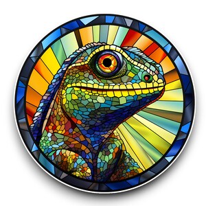 May include: A colourful stained glass design of a lizard with a bright orange eye. The lizard is surrounded by a circular frame with a blue border and a yellow and orange background.