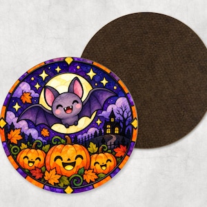 May include: A round drink coaster featuring a stained-glass style illustration of a smiling purple bat flying in front of a full moon, with three orange jack-o'-lanterns, autumn leaves, and a dark house silhouette below.
