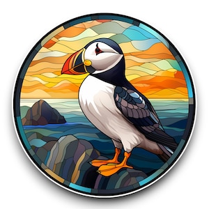May include: A stained glass illustration of a puffin standing on a rocky cliff overlooking a blue sea. The background features a colourful sunset with orange, yellow, and blue hues.