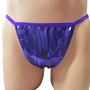 May include: A shiny, purple thong-style undergarment. The fabric has a metallic sheen, and the waistband and edges are a darker purple. The garment is designed to be minimal in coverage.