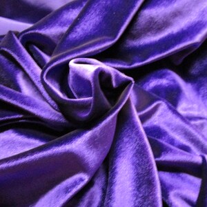 Puede incluir: Primer plano de una lujosa tela de terciopelo morado oscuro. La tela est&aacute; drapeada y doblada, creando sombras y reflejos que enfatizan su textura suave y brillo. Los pliegues crean una sensaci&oacute;n de profundidad y movimiento.