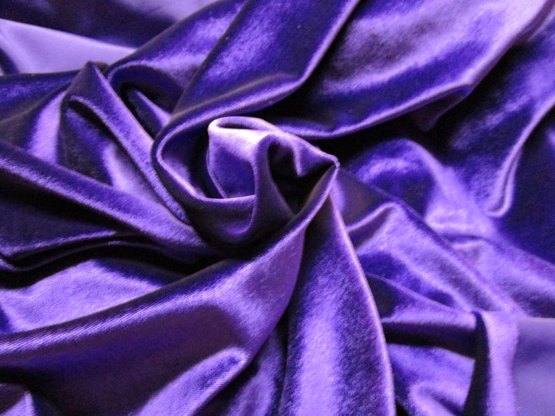 Puede incluir: Primer plano de una lujosa tela de terciopelo morado oscuro. La tela est&aacute; drapeada y doblada, creando sombras y reflejos que enfatizan su textura suave y brillo. Los pliegues crean una sensaci&oacute;n de profundidad y movimiento.