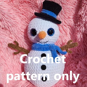 May include: White crocheted snowman with a blue scarf and black top hat. The snowman has black eyes and a carrot nose. The text "Crochet pattern only" is written below the snowman.