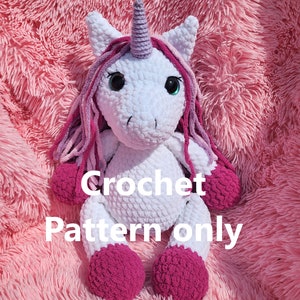 May include: Crochet pattern for a white unicorn amigurumi with pink and purple yarn. The unicorn has a pink horn, pink hooves, and a pink and purple mane.