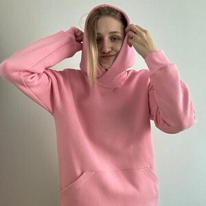 Op de afbeelding: Een roze hoodie met een kangoeroezak.