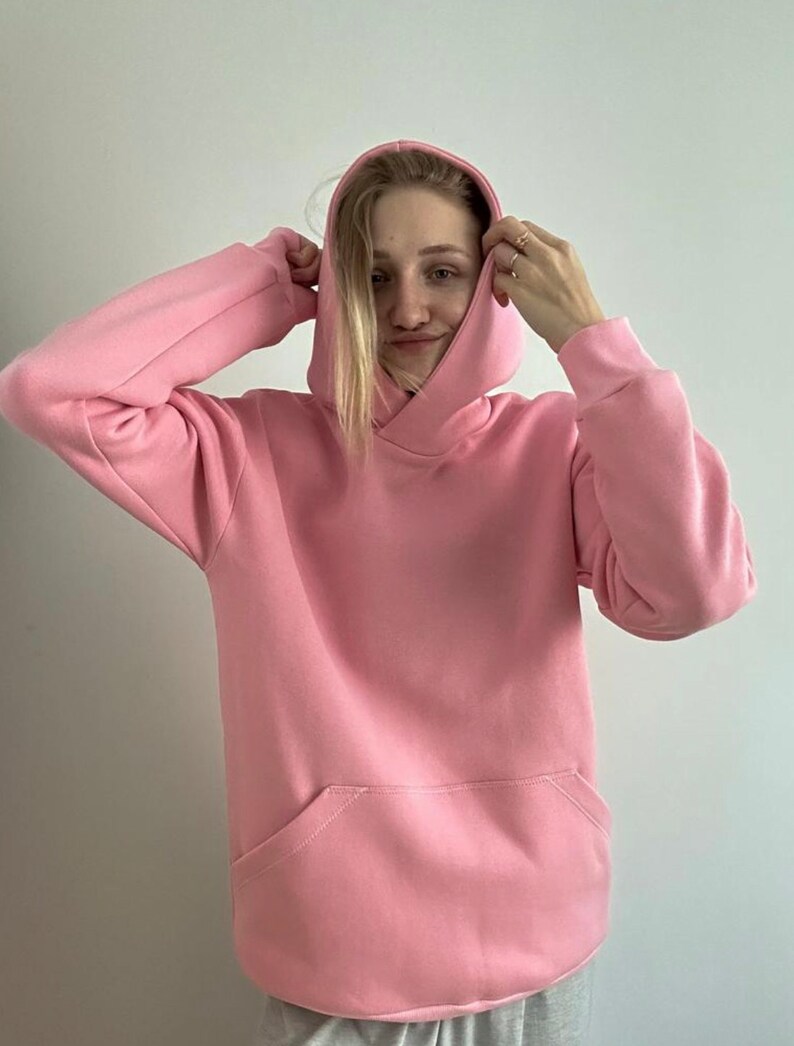 Op de afbeelding: Een roze hoodie met een kangoeroezak.