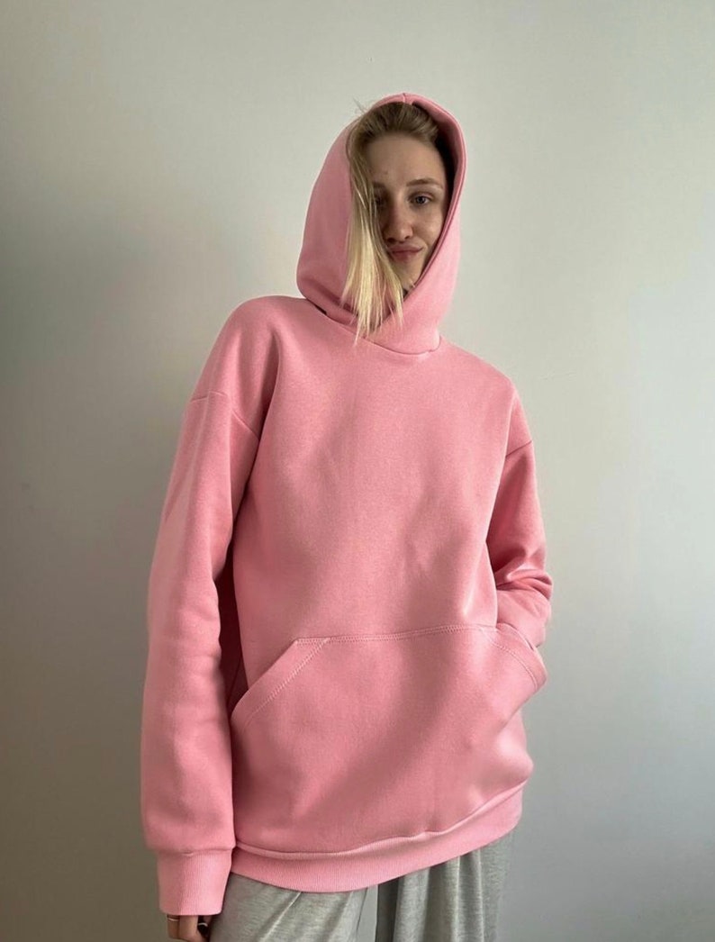 Op de afbeelding: Een roze oversized hoodie met een kangoeroezak. De hoodie heeft een capuchon met trekkoord.