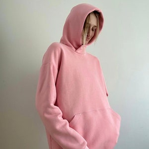 Op de afbeelding: Een roze oversized hoodie met een kangoeroezak. De hoodie heeft een capuchon met trekkoord.