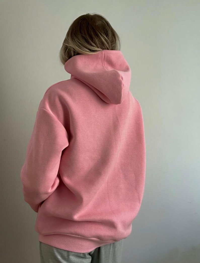 Op de afbeelding: Een roze hoodie met een capuchon met trekkoord.
