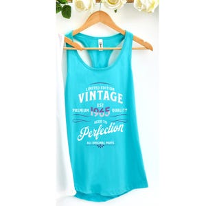 May include: Turquoise blue tank top with a white graphic that says "Limited Edition Vintage Est 1965 Premium Quality Aged to Perfection All Original Parts".