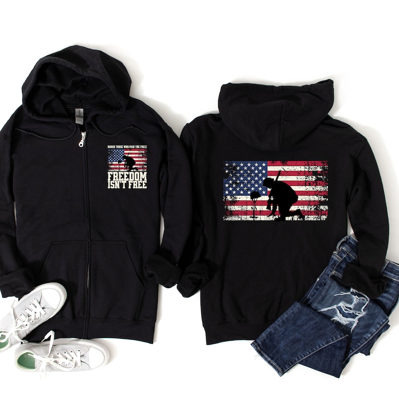 Puede incluir: Sudadera negra con cremallera y capucha, con una bandera americana desgastada en la espalda y el texto "Honor those who paid the price FREEDOM ISN'T FREE" en la parte delantera.