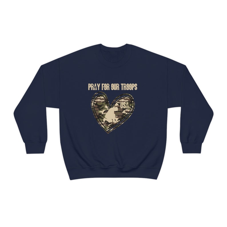 K&ouml;nnte beinhalten: Marineblauer Sweatshirt mit einem Tarnmusterherz und dem Text "Pray for our Troops" und "USA" in Wei&szlig;.