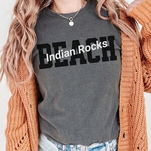 Puede incluir: Una camiseta gris oscura con el texto "Indian Rocks Beach" impreso en negro.