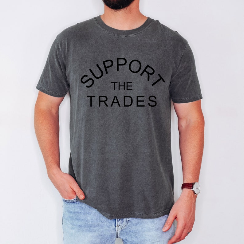 May include: A charcoal grey t-shirt with the text "SUPPORT THE TRADES" printed in black.