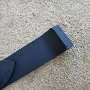 Puede incluir: Primer plano de una correa de reloj azul marino con una hebilla plateada. La correa est&aacute; hecha de un material liso y mate. La correa del reloj mide aproximadamente 2,5 cm de ancho.