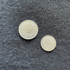 Puede incluir: Dos monedas de plata de Bulgaria. La moneda más grande es una moneda de 50 leva de 1930. La moneda más pequeña es una moneda de 20 leva de 1930.