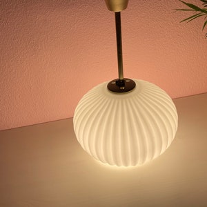 May include: A white, ribbed glass pendant light fixture with a gold metal stem.