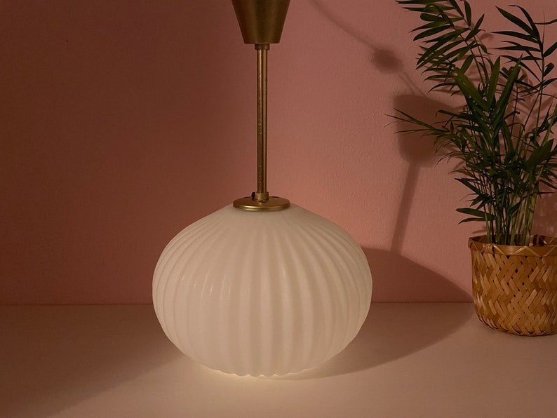 May include: A white, ribbed glass pendant light fixture with a gold metal base and stem.