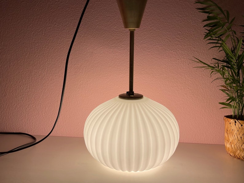 May include: A white, ribbed glass pendant light fixture with a gold metal base and a black cord.
