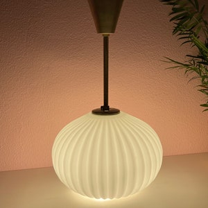 May include: A white ribbed glass pendant light fixture with a brass stem and a white ceiling mount.