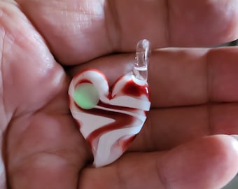 May include: A white and red glass heart pendant with a swirl pattern. The heart has a clear glass bead in the center.
