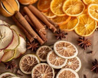 May include: A collection of dried citrus fruits, including orange slices and whole oranges, along with cinnamon sticks, star anise, and dried apple slices. The arrangement is set on a brown paper surface, creating a rustic and natural aesthetic.