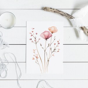 K&ouml;nnte beinhalten: Ein Aquarellbild von rosa und pfirsichfarbenen Blumen mit braunen Stielen und kleinen rosa Knospen. Das Bild ist auf wei&szlig;em Hintergrund und wird von einem wei&szlig;en Passepartout gerahmt.