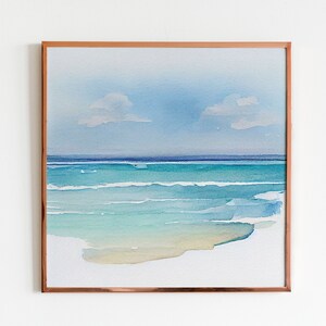 Puede incluir: Pintura de acuarela enmarcada de una escena de playa. La obra representa un oc&eacute;ano sereno con tonos turquesa y azul, un cielo azul claro y dos peque&ntilde;as nubes. El marco es de color cobre, lo que se suma a la est&eacute;tica.