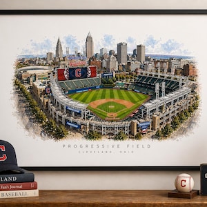Könnte beinhalten: Ein gerahmter Aquarelldruck von Progressive Field in Cleveland, Ohio. Das Baseballstadion wird mit einem grünen Feld, Sitzbereichen und der Skyline der Stadt im Hintergrund dargestellt. Vor dem Druck liegt eine schwarze Baseballkappe mit einem roten "C".