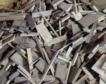 May include: A large pile of wood scraps in various shades of brown and gray. The wood is in different sizes and shapes, some are long and thin, others are short and wide.