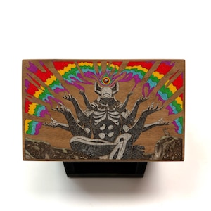 May include: Wooden box featuring a detailed illustration of a figure with multiple arms, seated in a meditative pose. The artwork includes a rainbow-colored burst emanating from the figure's head. The box has a natural wood grain finish.