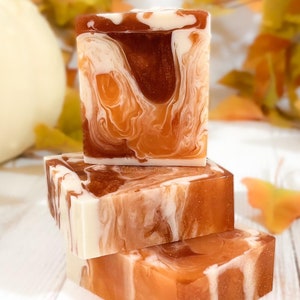 May include: Three bars of handmade soap stacked on top of each other. The soap is a swirl of brown, orange, and white.