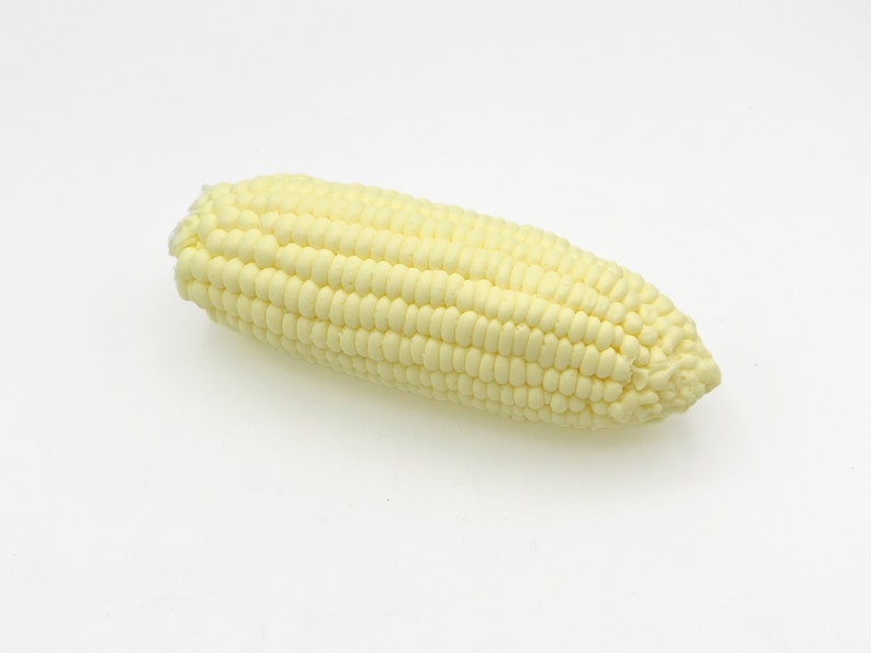 May include: A single ear of white corn, with the husks removed, on a white background.