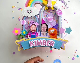May include: A colorful cake topper with a rainbow, clouds, stars, and a photo of a girl and a woman. The topper says "Hi Friends!" and "Kimber".