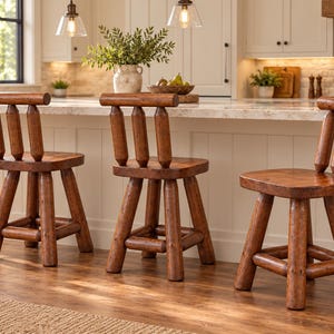 May include: Three wooden bar stools with a medium brown finish, each featuring a square seat, a low backrest with three vertical cylindrical spindles, and four thick, sturdy legs connected by horizontal support rungs near the base.