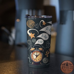 May include: A black and white tumbler with a graphic of an alarm clock and the words "5:15", "5:30", and "5:45" in speech bubbles. The tumbler has a black lid with a silver ring.