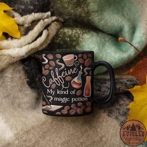 Op de afbeelding: Zwarte koffiemok met de tekst "Caffeine, My kind of magic potion" in witte letters. Versierd met koffiebonen en illustraties van drankjes. De mok heeft een zwart oor en staat op een getextureerde achtergrond. Een leuk cadeau.