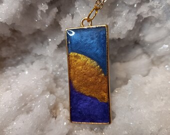 Collier unique en résine tricolore, bleu, or, violet en lunette dorée sur chaîne en or