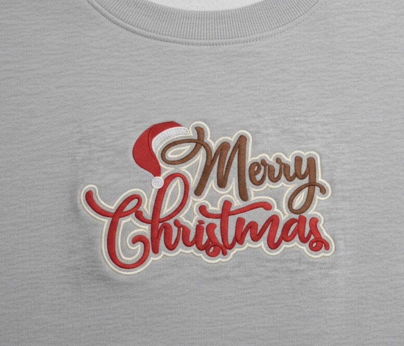 Puede incluir: Sudadera gris claro con la frase bordada "Merry Christmas" en escritura roja y marr&oacute;n. Un gorro de Pap&aacute; Noel est&aacute; incorporado en el dise&ntilde;o, a&ntilde;adiendo un toque festivo a la ropa navide&ntilde;a.