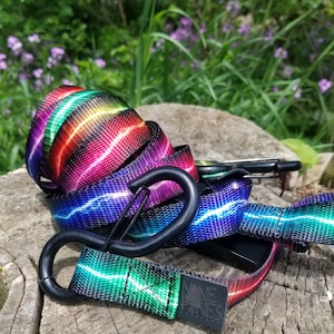 May include: A colorful, rainbow-striped, black webbing strap with a black carabiner clip. The strap is made of durable nylon and features a lightning bolt design.
