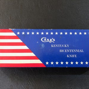 May include: Rectangular box with a patriotic design. The left side features red and white stripes, while the right side is blue with white stars. Text on the box reads "Case's Kentucky Bicentennial Knife."